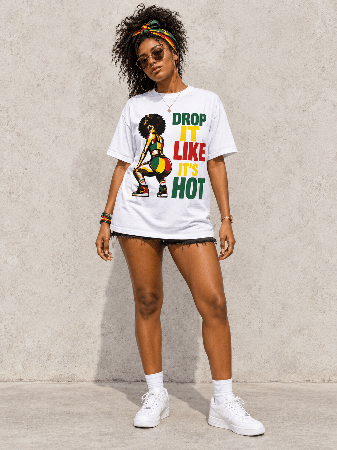 Model wearing Drop It Like It’s Hot Carnival Tee, front view showing the design, against a light concrete backdrop.
