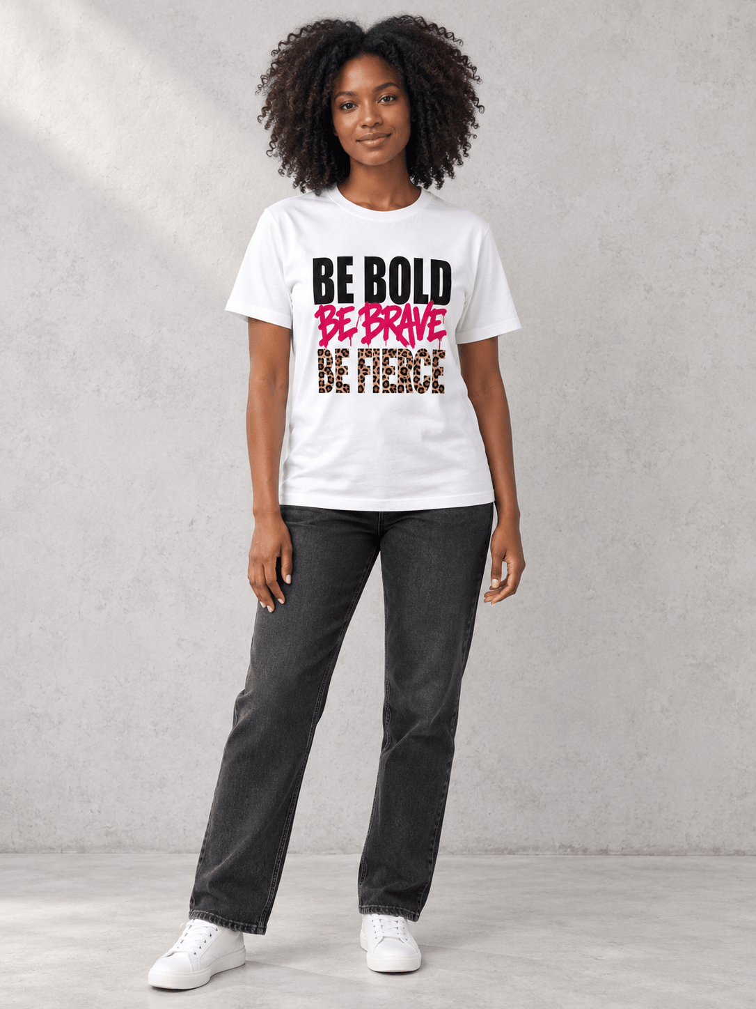 Model wearing Moda Originals Be Bold Tee, front view showing the design, against a light concrete backdrop.