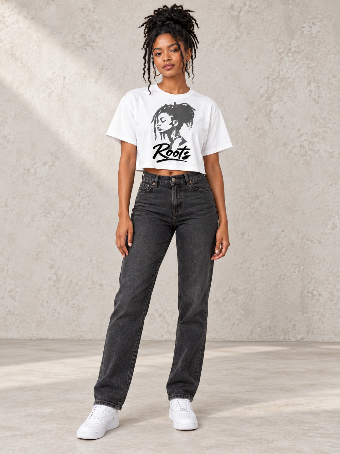 Model wearing Moda Originals Roots Crop Tee, front view showing the design, against a light concrete backdrop.