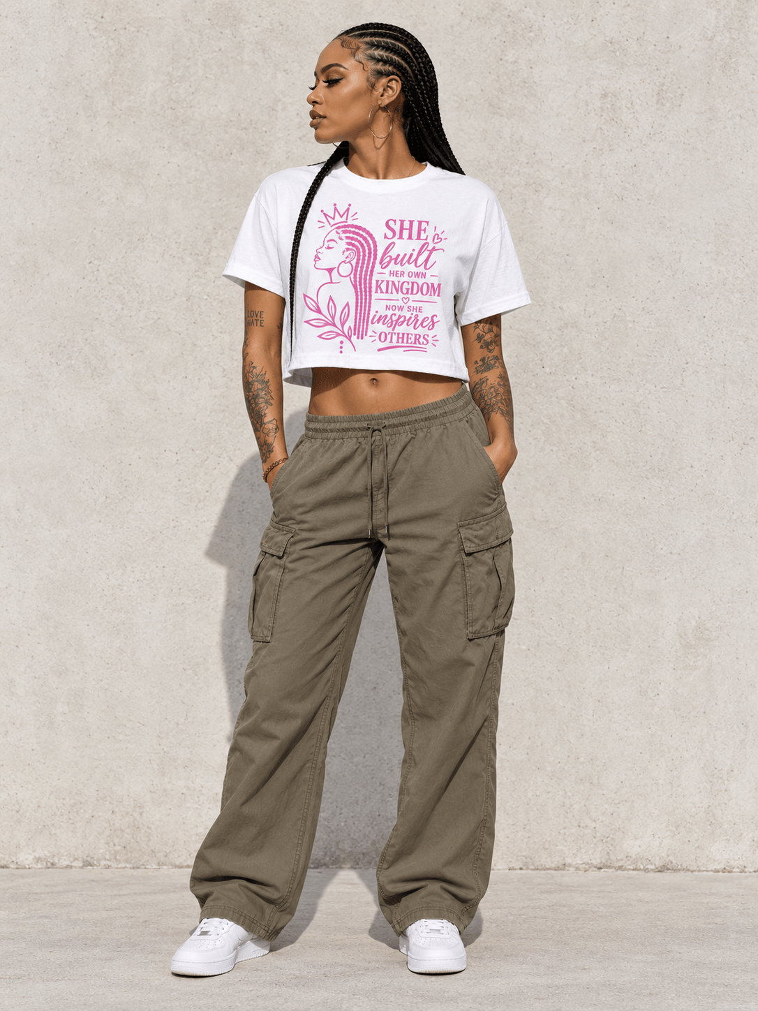 Model wearing She Built Her Own Kingdom Crop Tee, front view showing the design, against a light concrete backdrop.
