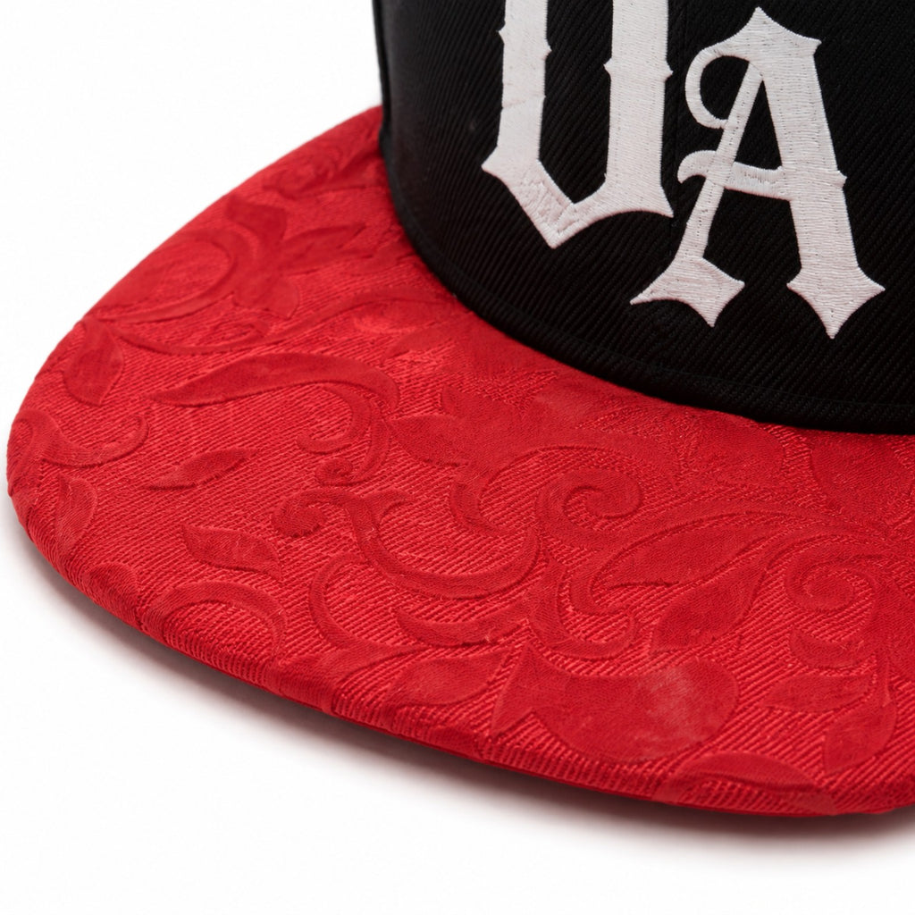 Close-up of white UA logo and red patterned peak on Urban Avenue cap.