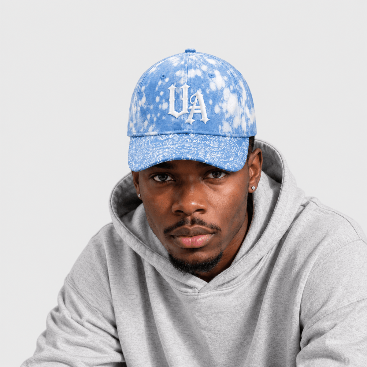 Model wearing Urban Avenue light blue and white baseball cap against a light grey catalogue background.