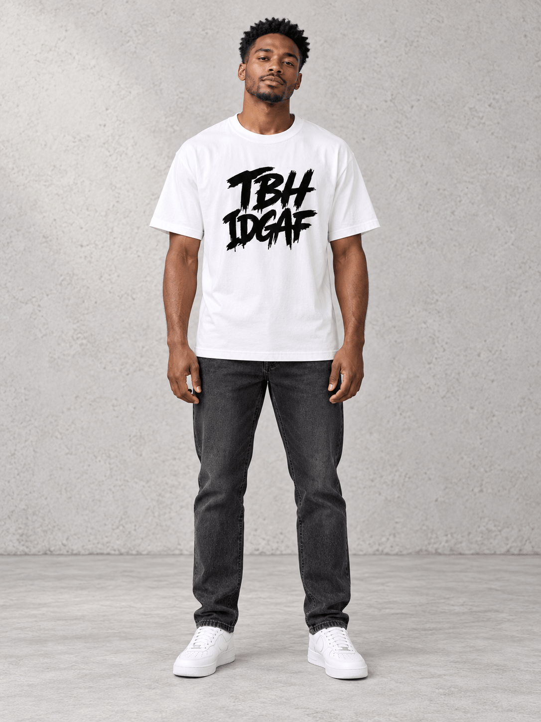 Model wearing Urban Avenue TBH IDGAF Tee, front view showing the design, against a light concrete backdrop.
