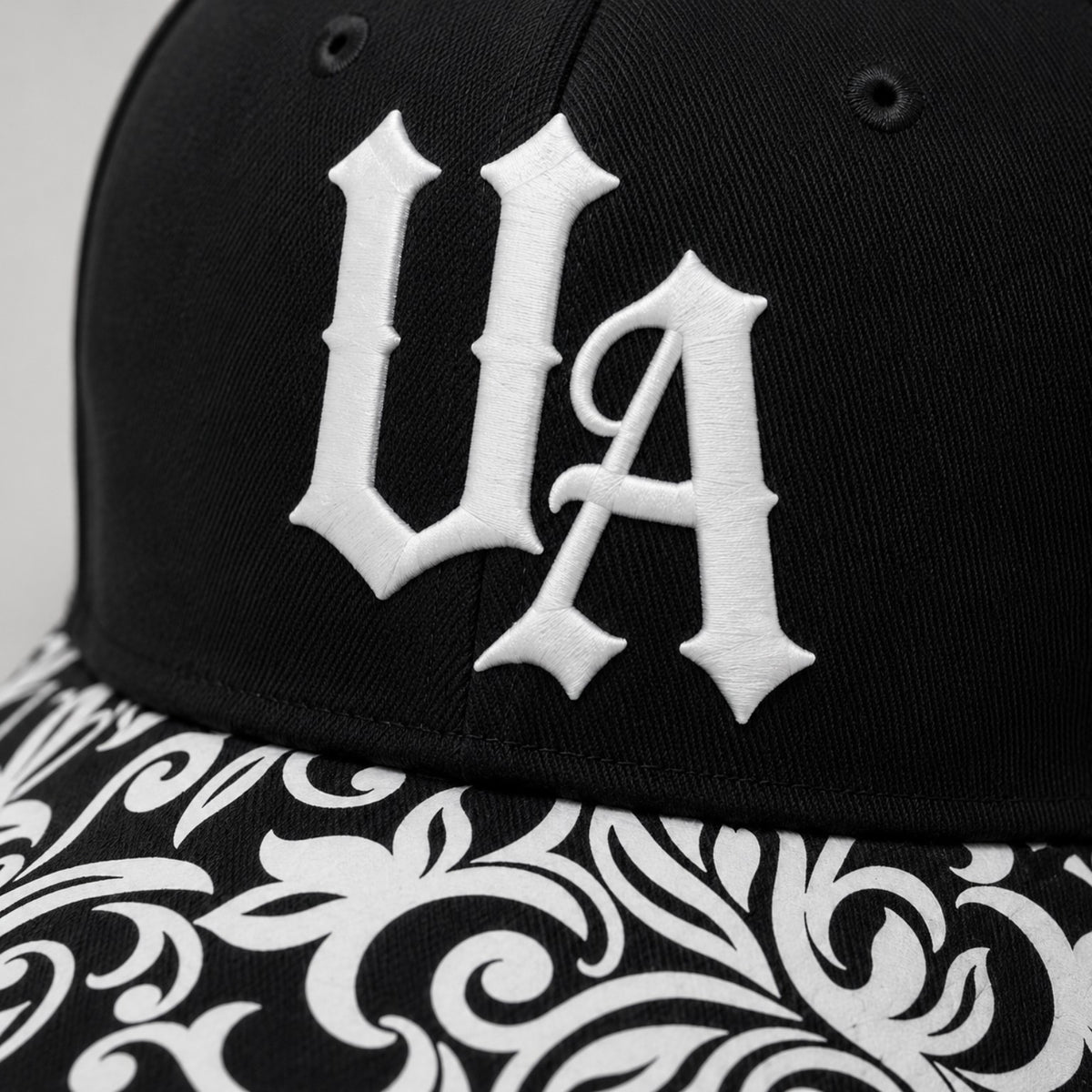Urban Avenue UA baseball cap in black and white, logo detail view.